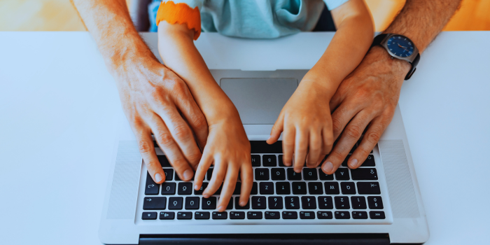 Adult and child's hands on a laptop keyboard